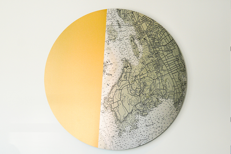 round wall art with left half in brass and right half an engraved silver and brass map of newport